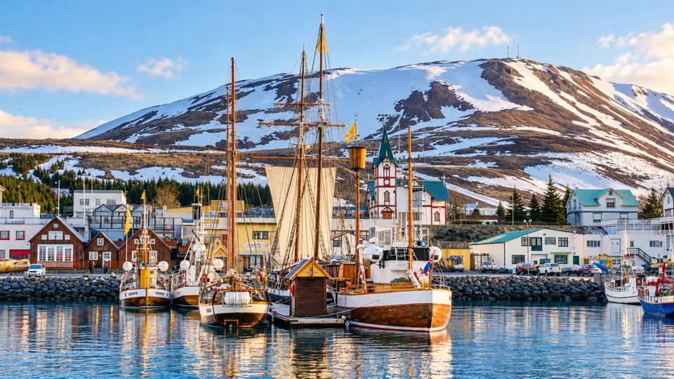 Husavik harbor with wooden boats and snowy coastal mountains