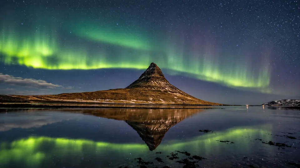 Kirkjufell mountain and water under restrained green aurora