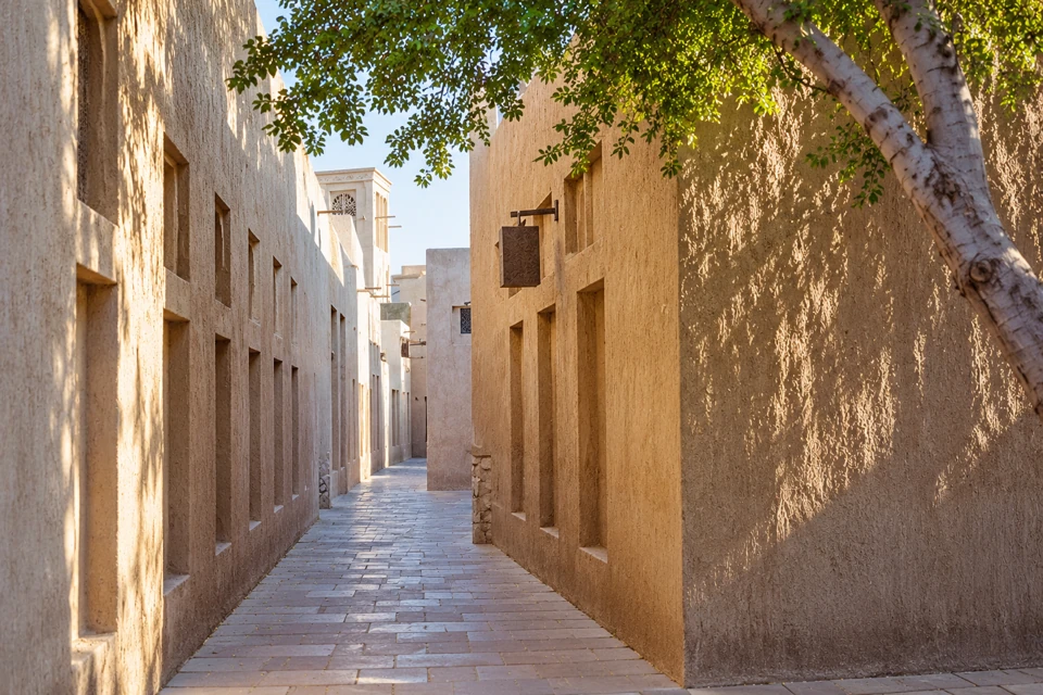 A shaded stone-paved lane and traditional wind tower in Al Fahidi, Bur Dubai.