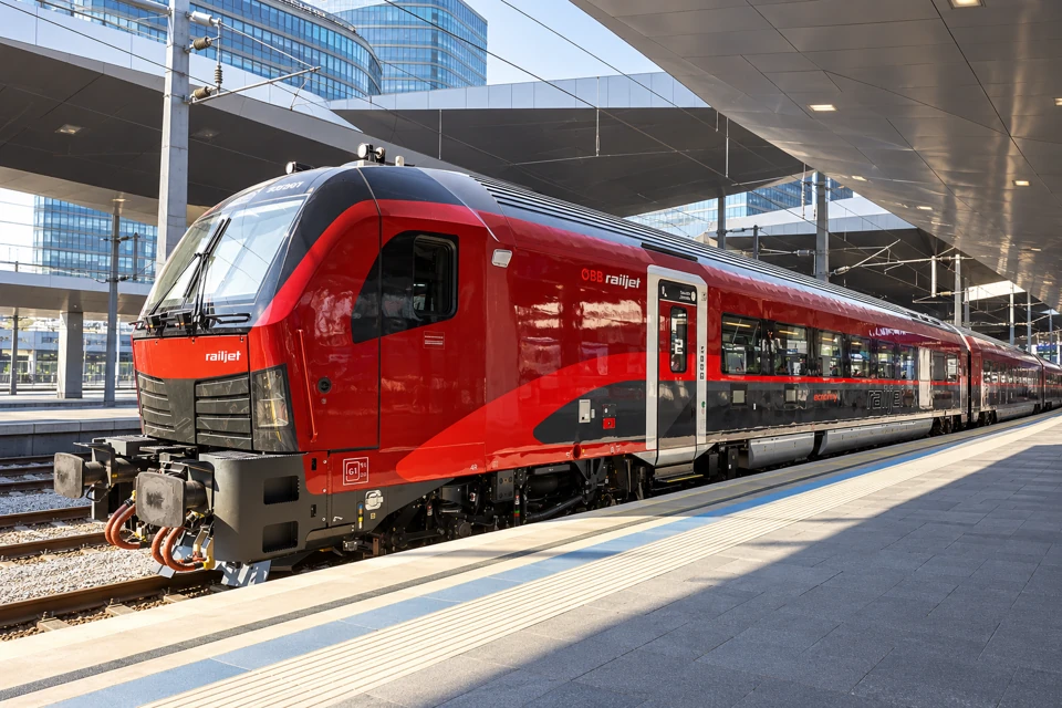 Red and charcoal new-generation ÖBB Railjet cab car at Vienna Hauptbahnhof.