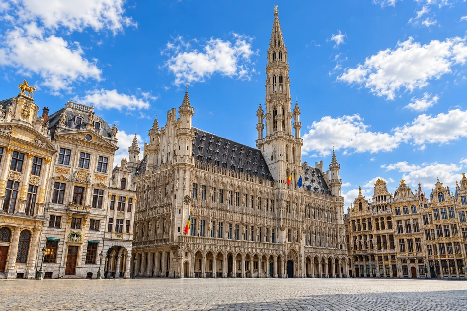 Brussels Town Hall's tall Gothic spire and ornate stone facade above the cobblestones of Grand-Place.