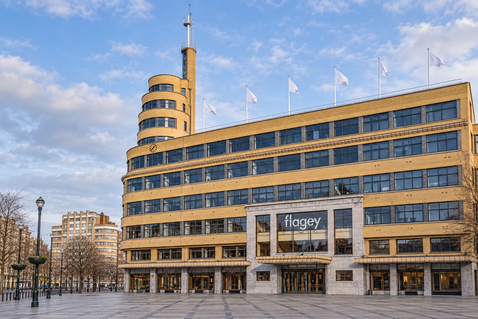Flagey's yellow-brick facade with horizontal window bands, rounded tower and stone-framed entrance in Brussels.