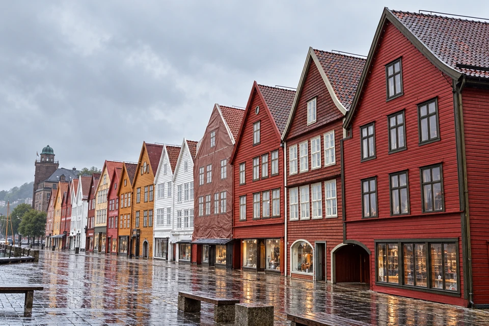 Bryggen's red, ochre and white timber gables beside a rain-wet stone quay in Bergen.