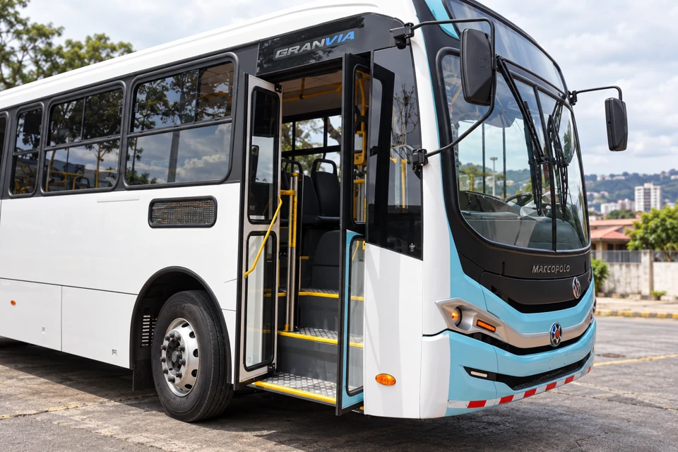 A Costa Rican city bus with a white body, pale turquoise front bands and open front entrance showing yellow-edged steps and handrails.