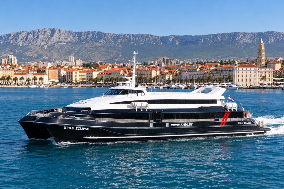 Krilo Eclipse passenger catamaran with dark twin hulls and white upper cabin in front of Split's waterfront.
