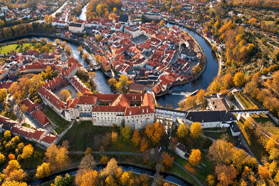 Cesky Krumlov's red-roofed old town inside the Vltava River bend, with its castle and autumn trees.
