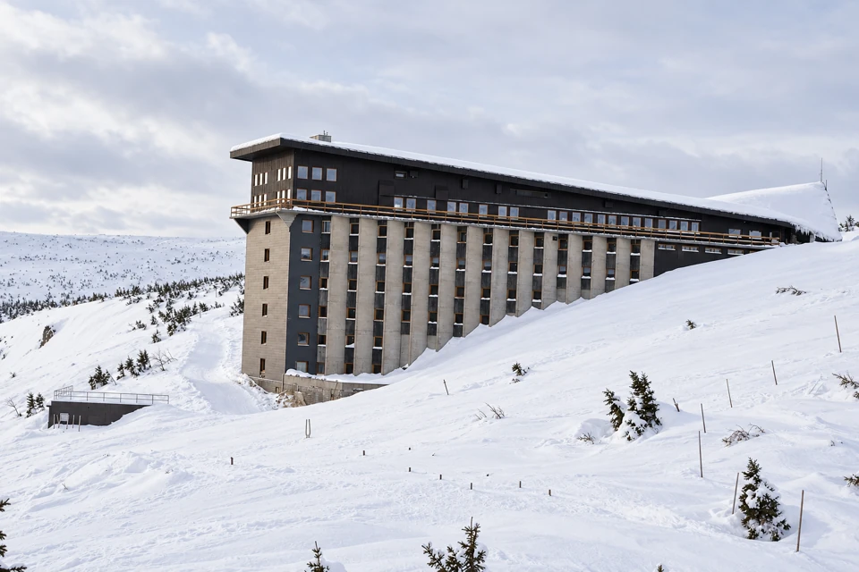 Labska bouda's long modern concrete facade above a steep snow-covered slope in the Krkonose mountains.