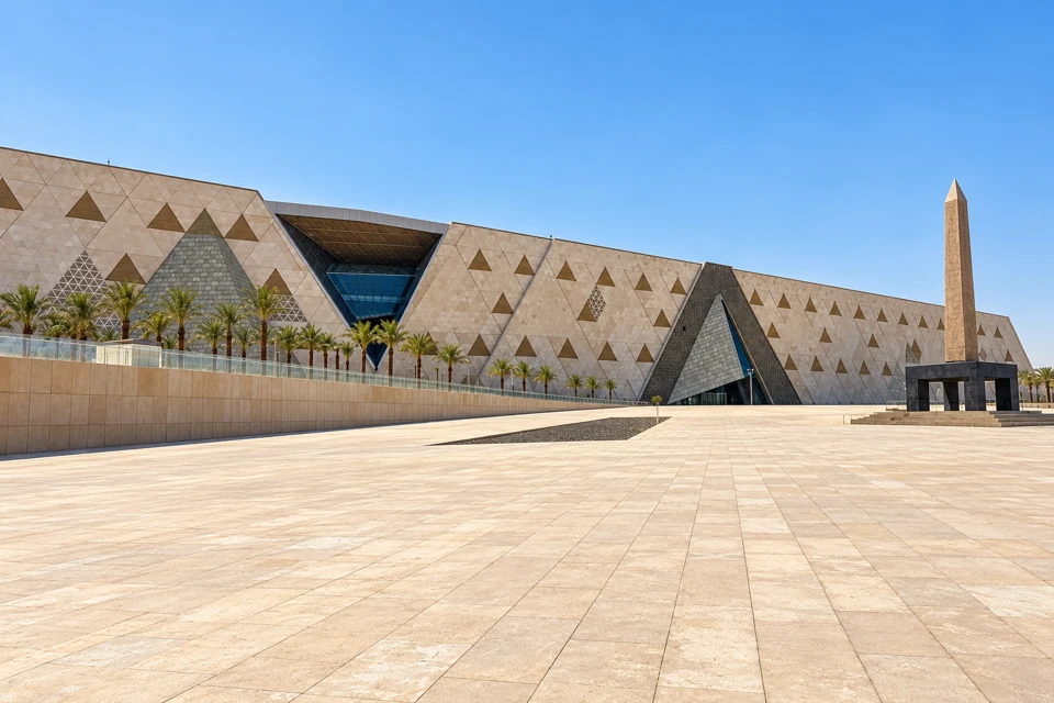 The Grand Egyptian Museum's triangular stone facade, entrance plaza and standing obelisk at Giza.