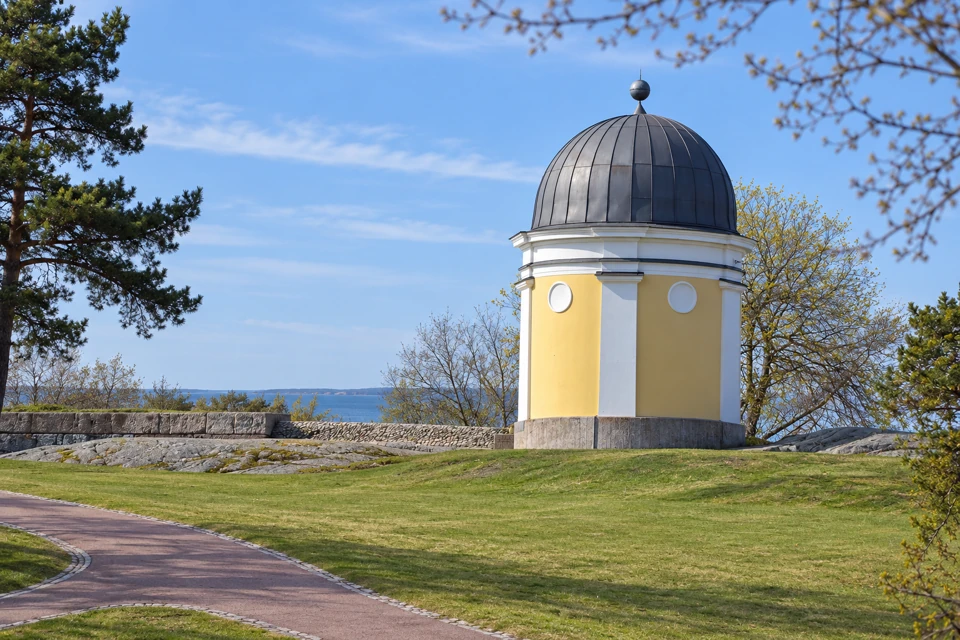 The small yellow Ursa Observatory above granite outcrops and early spring lawns in Helsinki's Kaivopuisto Park.