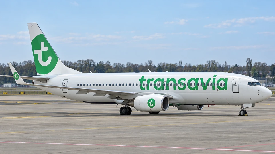 Transavia Boeing 737-800 with a white fuselage, green titles and a green-and-white tail on an airport apron.
