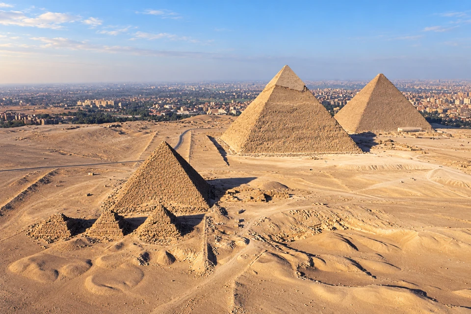 The three main Giza pyramids and smaller subsidiary pyramids above the desert plateau.