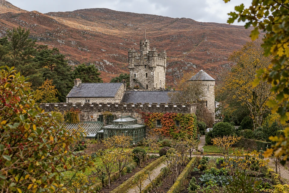 Glenveagh Castle above its garden beds, glasshouse and russet autumn ivy.