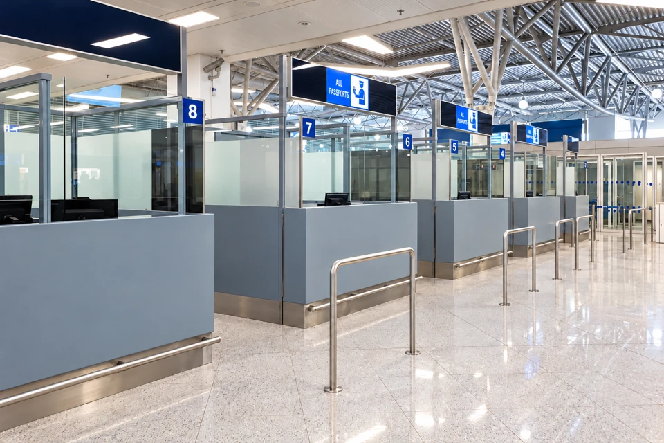 Staffed passport-control booths at Athens Airport with blue All Passports signs