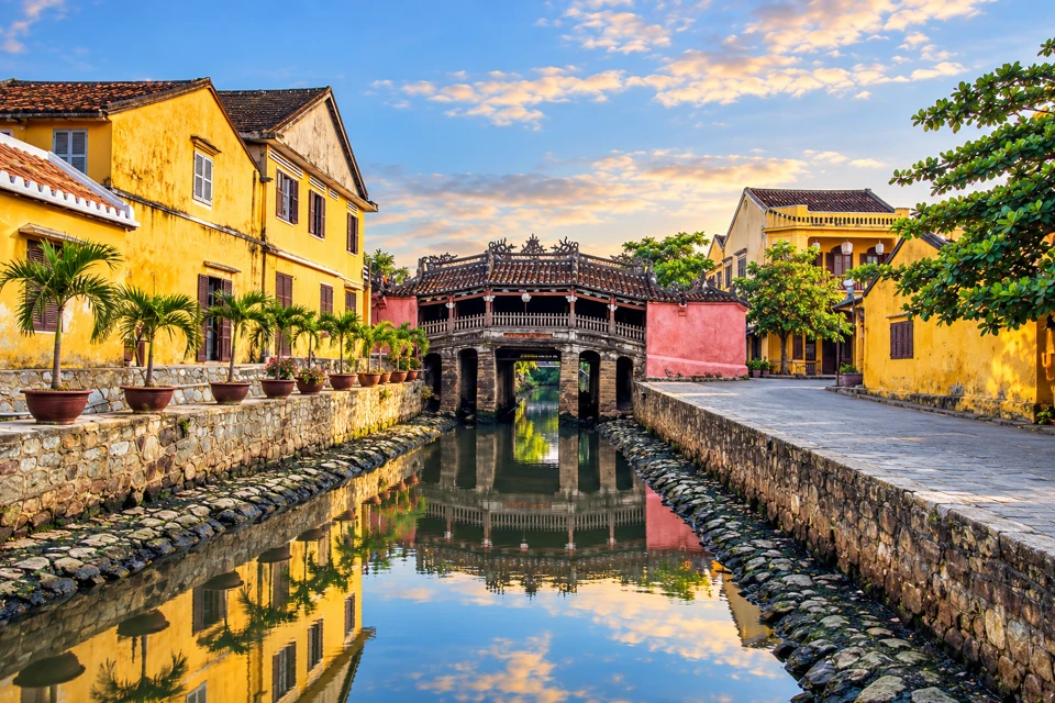 Hoi An's Japanese Covered Bridge spans a narrow canal between yellow heritage houses and stone banks.