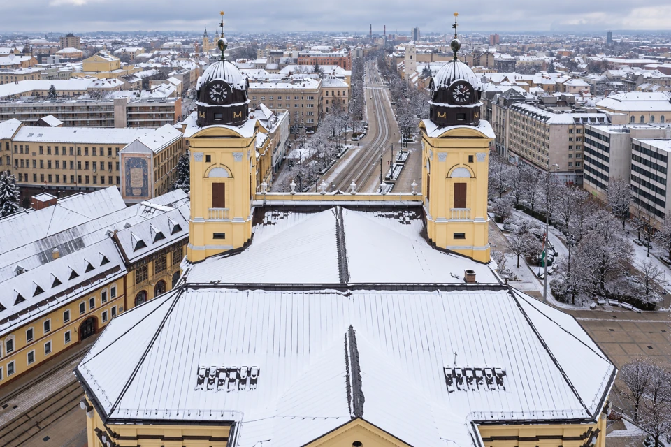 Debrecen's yellow Great Church towers and broad snow-covered roof above the city's winter streets.