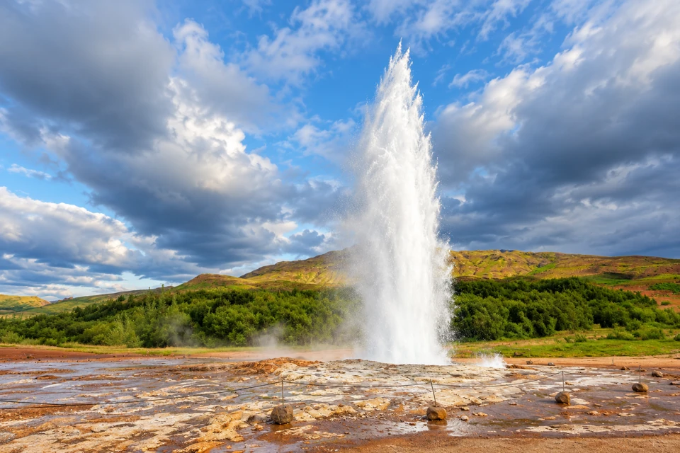 Strokkur erupting above the mineral field in Iceland's Geysir geothermal area.
