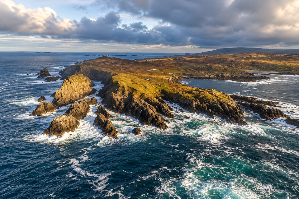 Atlantic surf around Malin Head's jagged rock spurs and low grassy headland.