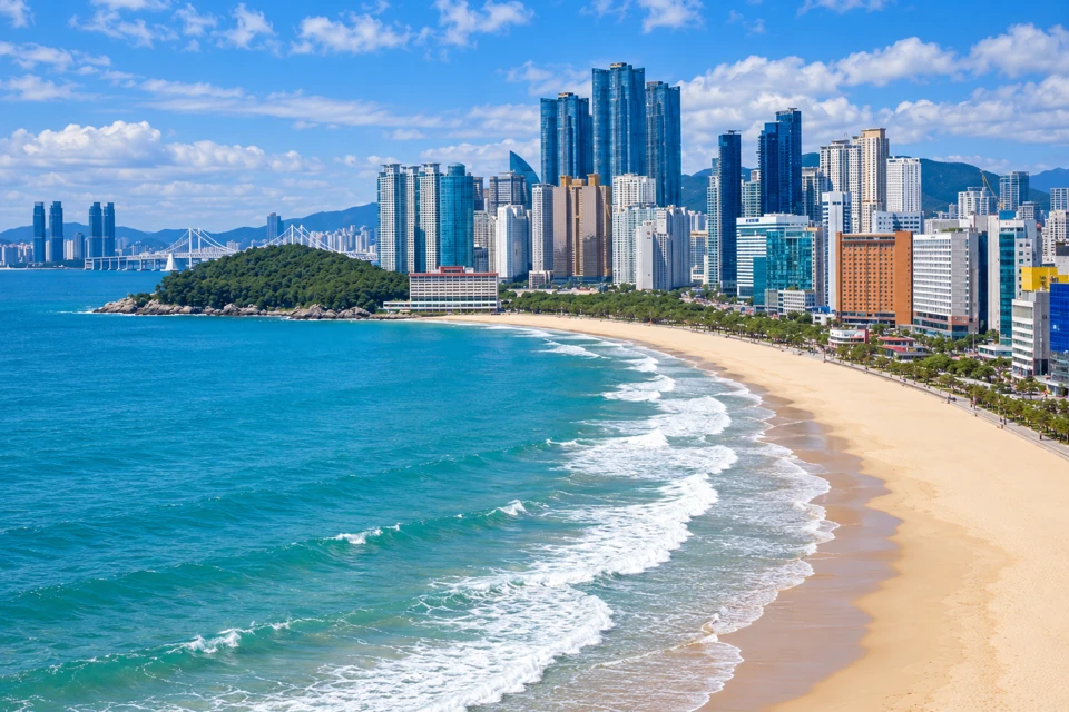 The curving sand and surf at Busan's Haeundae Beach, with Dongbaekseom and Marine City towers beyond.