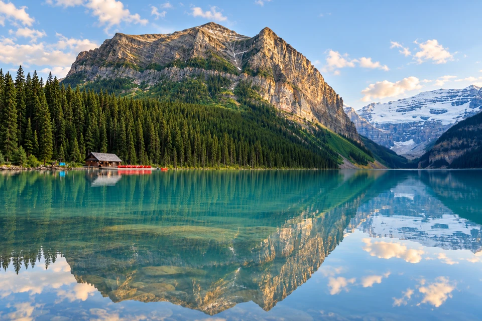 Lake Louise with its lakeside boathouse, forested mountains and distant glacier.