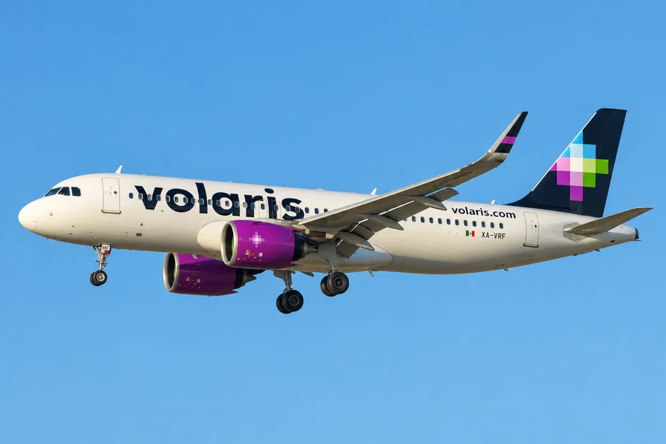 Volaris Airbus A320neo with purple engines and a black tail carrying the multicolored pixel-cross emblem.