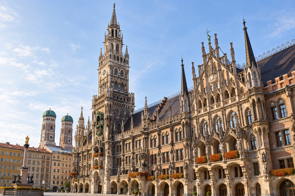 Munich's ornate New Town Hall at Marienplatz, with the twin green-domed Frauenkirche towers behind.