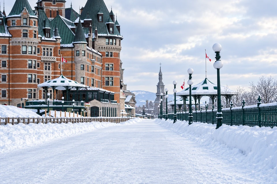 Snow covers Terrasse Dufferin beside Chateau Frontenac and green pavilion kiosks in Quebec City.