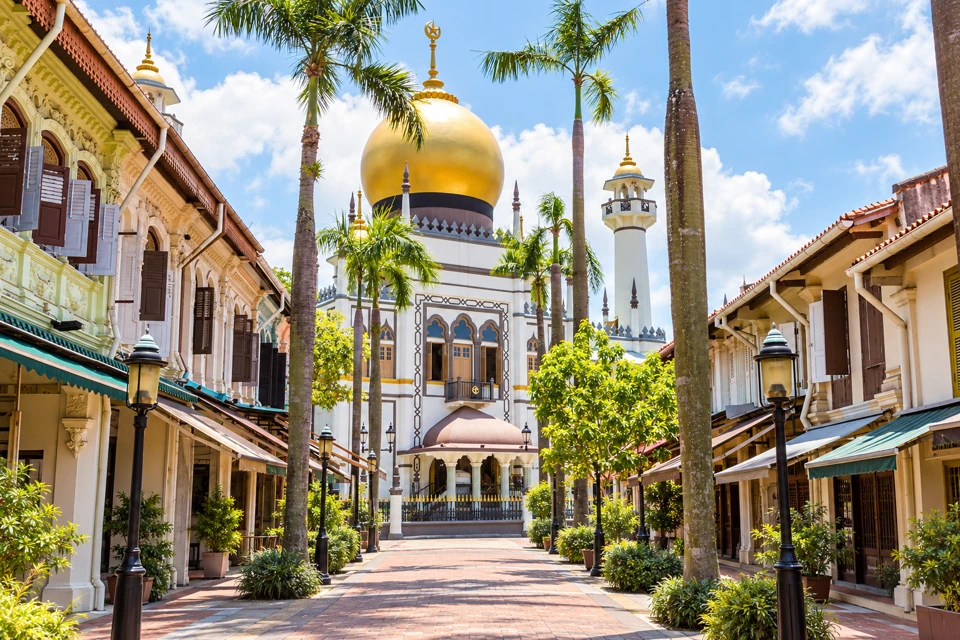 Sultan Mosque gold dome and white minarets at the end of palm-lined Bussorah Street in Kampong Glam