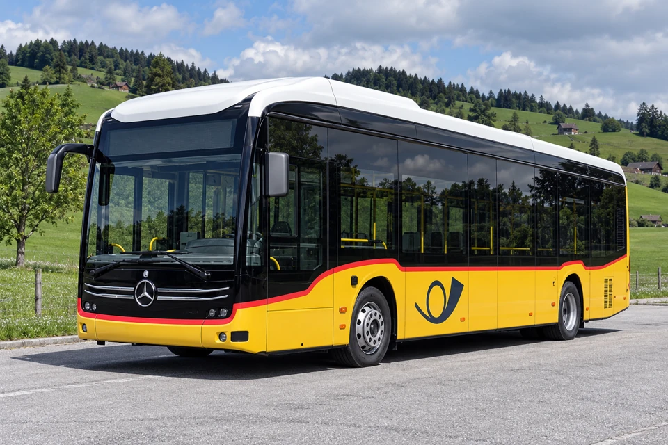 Yellow PostAuto Mercedes regional bus with dark upper glazing, white roof, thin red stripe and postal-horn side logo.