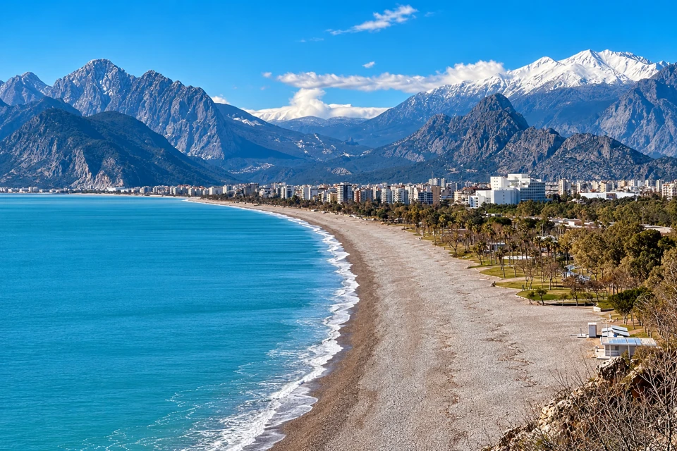 Konyaalti pebble beach and Antalya waterfront below the Beydaglari mountains with snow on high peaks