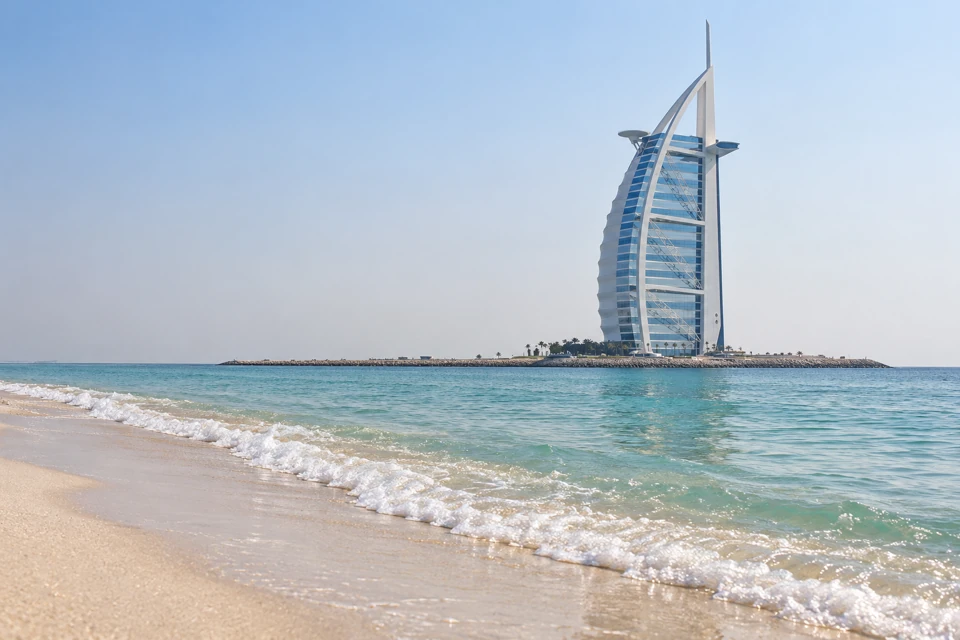 Gentle Gulf waves meet the pale Umm Suqeim shoreline in Dubai, with Burj Al Arab on its offshore island.