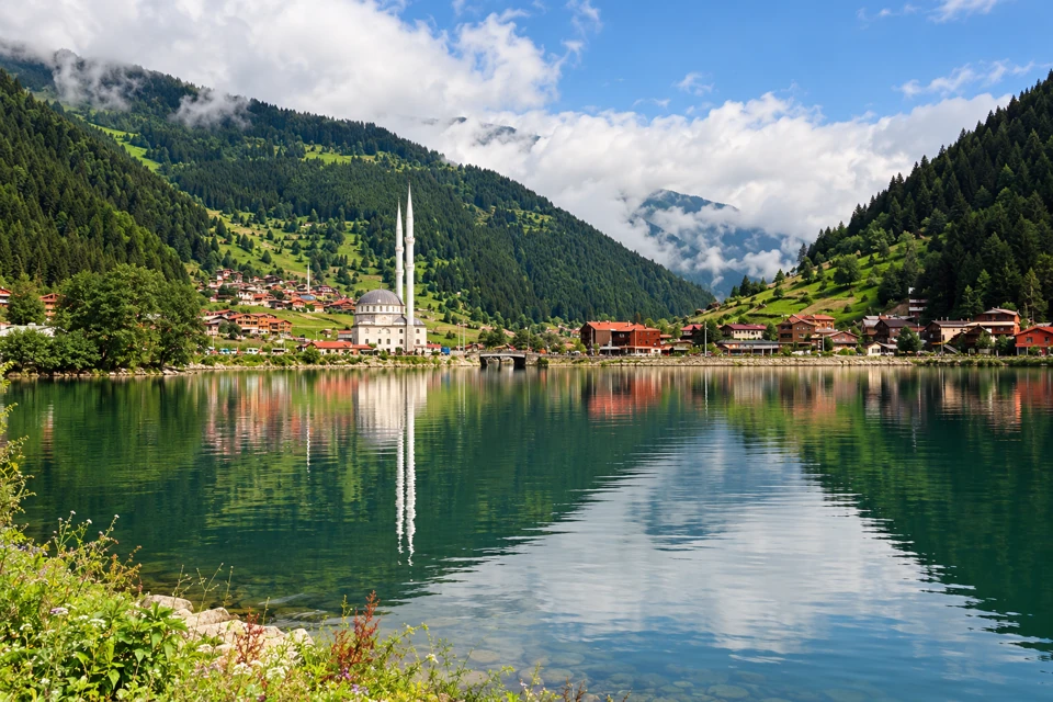 Uzungol lake and its twin-minaret mosque beneath green forested slopes in Turkey's Black Sea region.