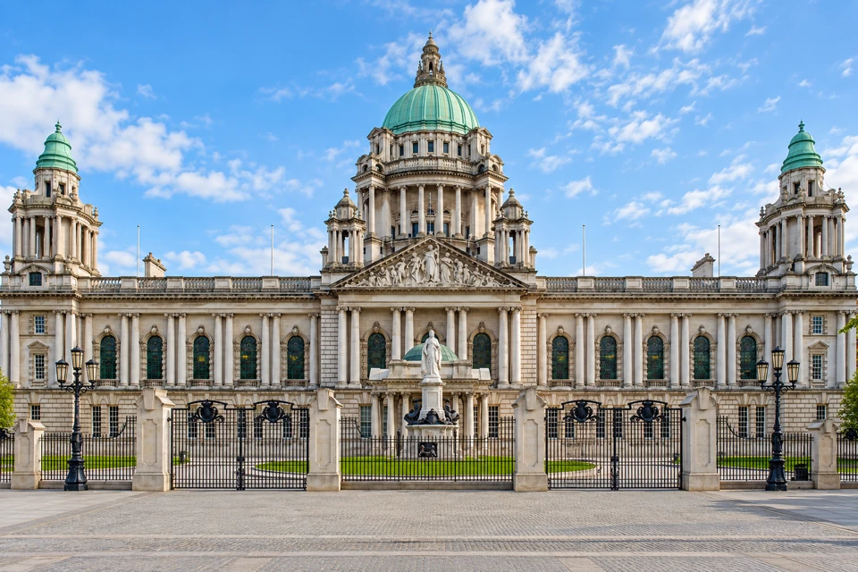 Belfast City Hall's green central dome, columned portico and symmetrical wings behind the front gates on Donegall Square.