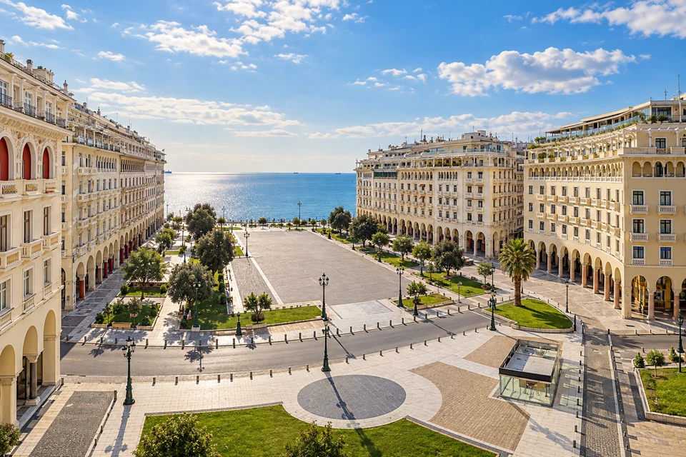 Thessaloniki's broad Aristotelous Square between pale curved buildings, opening toward the blue Thermaic Gulf.